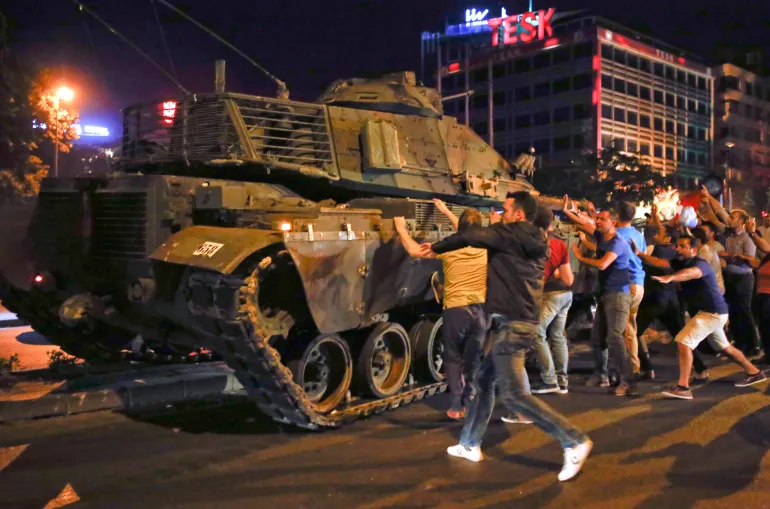 Des personnes réagissent près d'un véhicule militaire lors d'une tentative de coup d'État à Ankara, Turquie, le 16 juillet 2016.