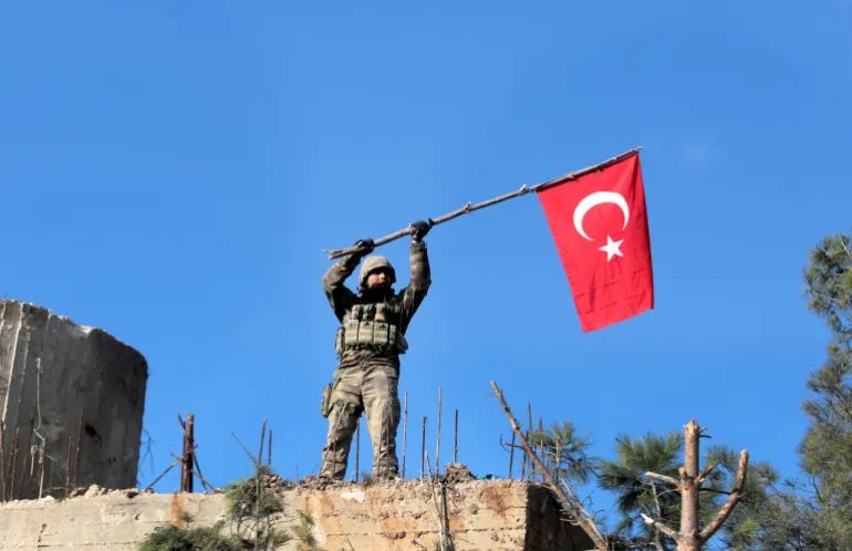 DOSSIER – Dans cette photo d'archive du dimanche 28 janvier 2018, un soldat brandit un drapeau turc alors que les troupes turques sécurisent la colline de Bursayah, qui sépare l'enclave kurde d'Afrin de la ville d'Azaz, sous contrôle turc, en Syrie. Le retrait prévu des troupes américaines ouvre un vide dans le nord et l’est de la Syrie, et les conflits et rivalités entre toutes les puissances du Moyen-Orient convergent pour le combler. (Photo AP, dossier)