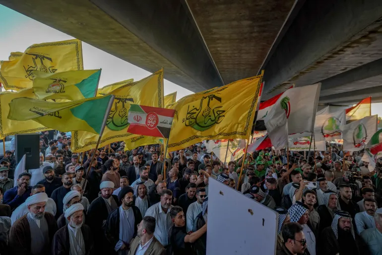 Des manifestants brandissent des drapeaux, notamment ceux de la milice irakienne Harakat Hezbollah al-Nujaba, alignée sur l'Iran, lors d'une manifestation contre la suspension des vols entre l'Irak et l'Iran devant l'aéroport international de Najaf, en Irak, le lundi 28 septembre 2026. (AP Photo/Anmar Khalil)