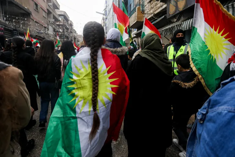 Une personne enveloppée dans un drapeau kurde participe à une manifestation des Kurdes syriens pour revendiquer leurs droits dans la constitution syrienne et en soutien à l'unité kurde, à Qamishli, en Syrie, le 1er février 2026.