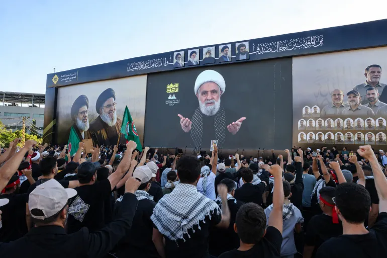 Des partisans du mouvement chiite libanais Hezbollah crient des slogans alors qu'ils regardent un discours télévisé du chef du Hezbollah Naim Qassem lors d'une cérémonie organisée pour marquer le deuxième anniversaire de l'assassinat de l'ancien dirigeant Hassan Nasrallah lors d'une frappe israélienne, dans la banlieue sud de Beyrouth, le 27 septembre 2026.